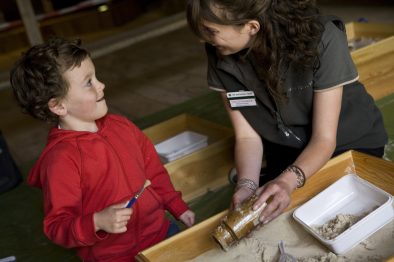 Child and a National Trust Visitor Services Assistant in the museum at Avebury, Wiltshire.