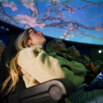 People sat in chairs looking up at projections of Van Gogh's work displayed across the planetarium dome