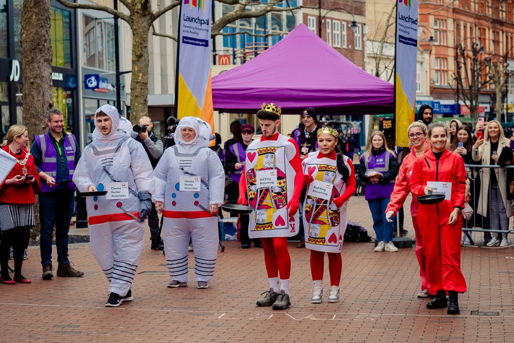 Pancake racegoers in fancy dress on high street