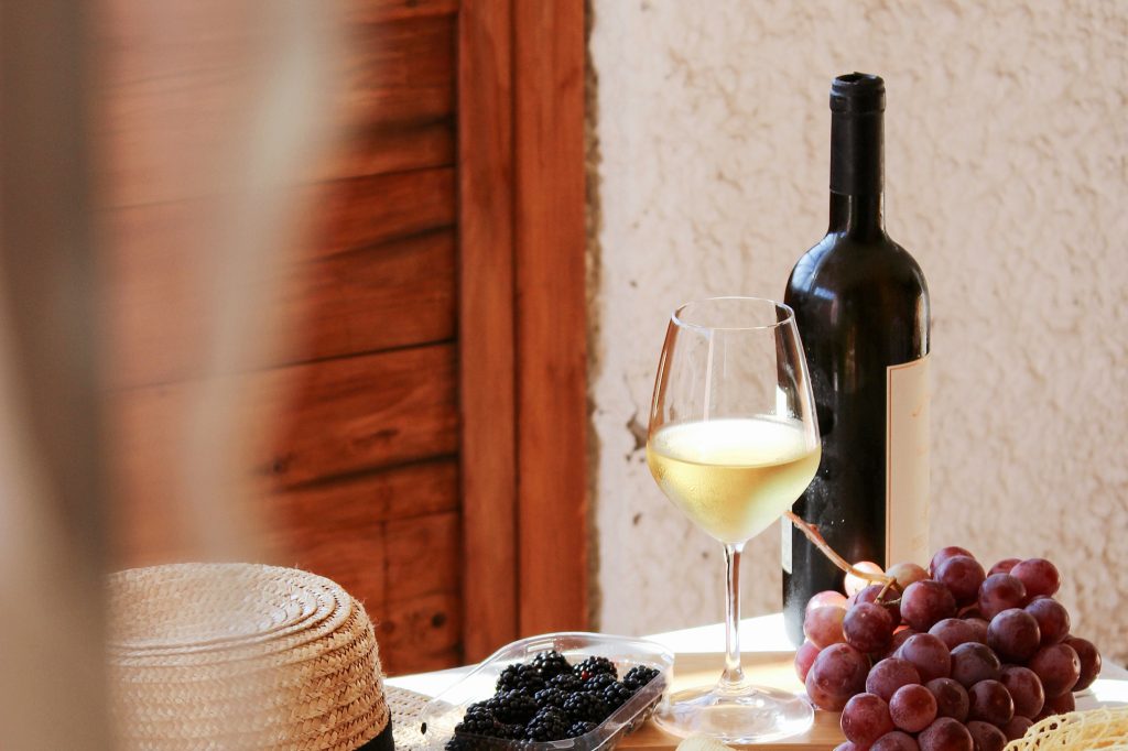 A table with a glass of wine, bottle of wine and grapes