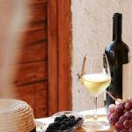 A table with a glass of wine, bottle of wine and grapes